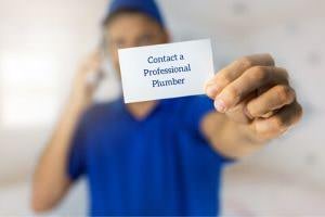 plumber holding a card that says "contact a professional plumber"