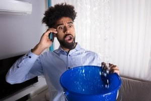 person on phone catching water leak in bucket
